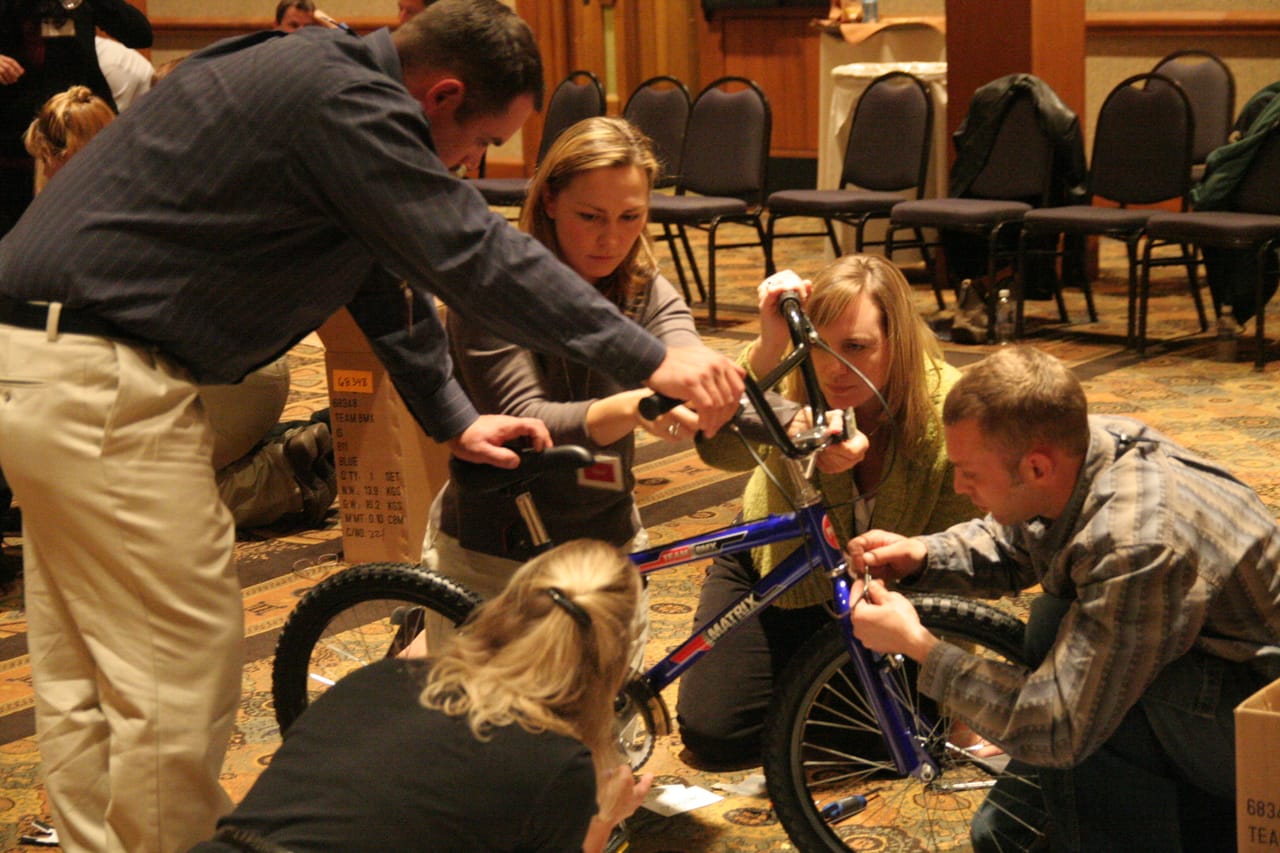 A corporate team assembling a real bike at a conference general session