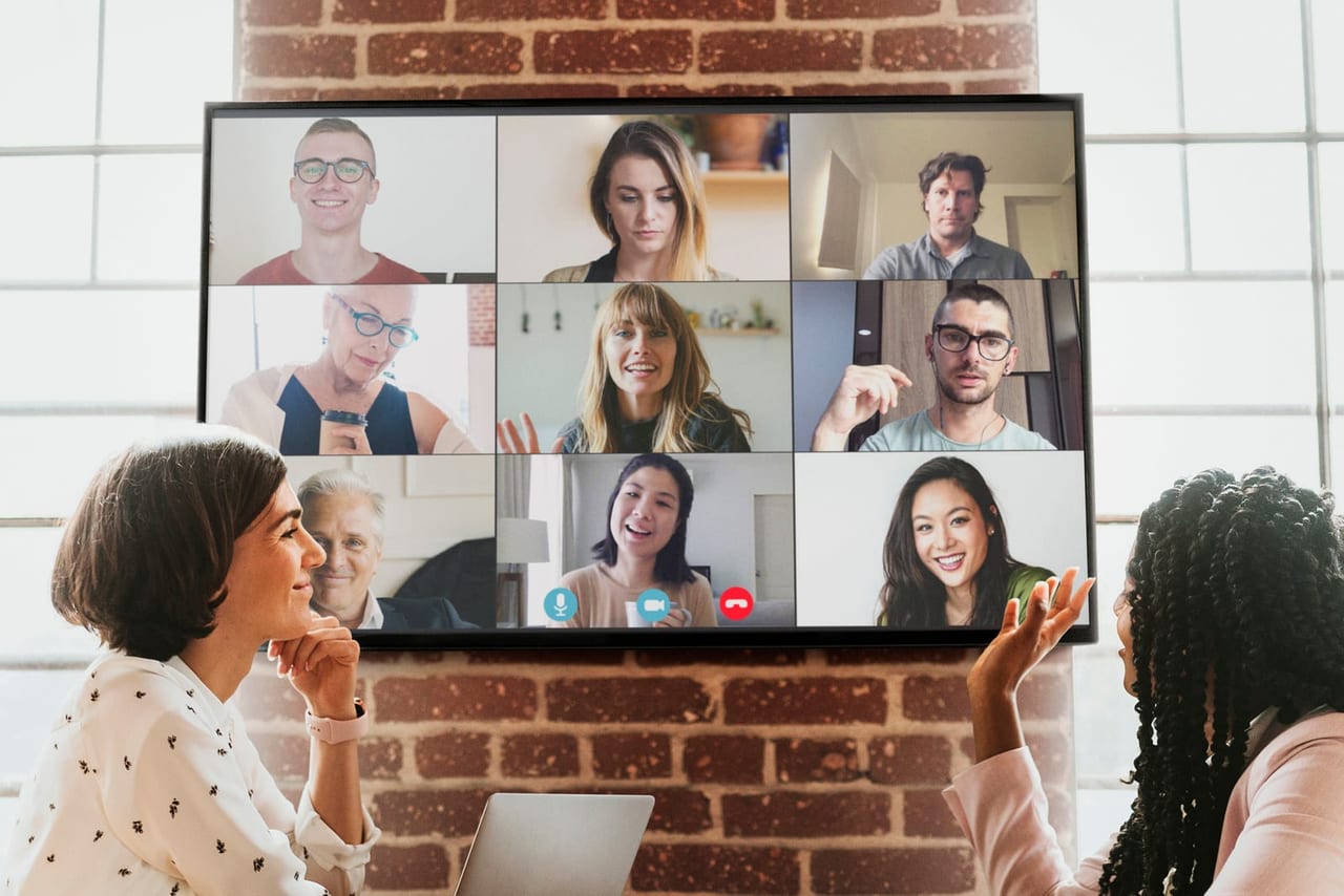 A hybrid team building event — in-room participants with remote colleagues on a video wall